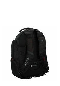 Mochila negra con tirantes de malla acolchada, múltiples compartimentos y acentos texturizados. Presenta un diseño que permite pasar el mango del equipaje.