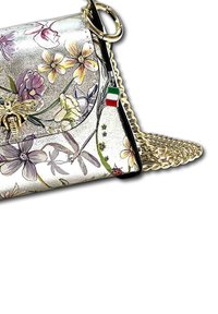 Handtas met bloemenprint en een glanzend zilveren oppervlak, gouden kettingband en een charm met de Italiaanse vlag. Vlindermotief accent.