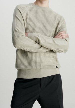 Hellgrauer strukturierter Pullover mit Karomuster, gerippten Bündchen und Saum, rundem Ausschnitt und taillierter Silhouette. Schwarzes Logo-Label am Saum.