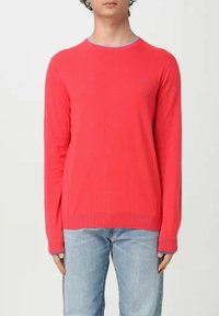 Maglione rosso con maniche lunghe, polsini e orlo a costine, scollatura rotonda bordata di azzurro chiaro, con un piccolo logo sul petto.