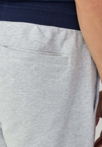 Grijze trainingsbroek met een marineblauwe tailleband, voorzien van een klein achterzakje, zachte textuur en een relaxte pasvorm.
