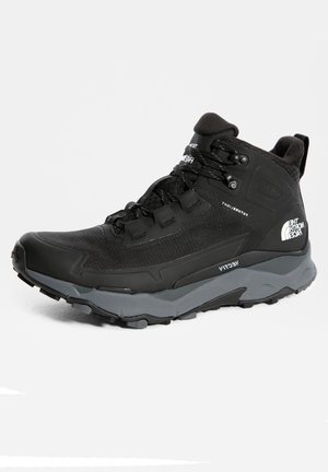Sort og grå vandrestøvle med midterhøjde, forstærket tå, tykke snørebånd, robust sål og The North Face-logo på hælen.