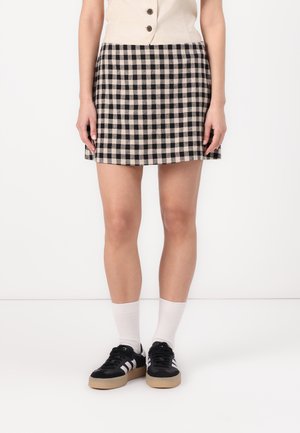 Svart og beige rutete mini skjørt med tilpasset liv, kombinert med svarte joggesko og hvite sokker. Glatt stoff og avslappet design.