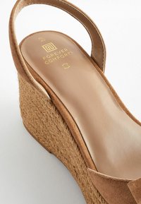 Sandale à talon compensé marron avec un talon en jute tressé, un dessus en daim doux et une semelle intérieure rembourrée arborant le logo "Forever Comfort" en doré.