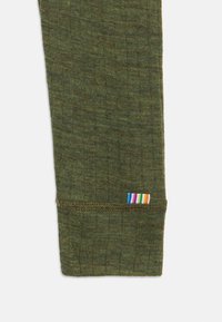 Zaļa adīta auduma legingas aproce ar daudzkrāsainu svītrainu etiķeti malā. Tekstūra izskatās mīksta un elastīga.