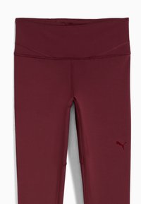 Burgundské legíny s širokým pasem, vyrobené z pružného materiálu. Na dolní části levé nohy se nachází malá, tónová logo.