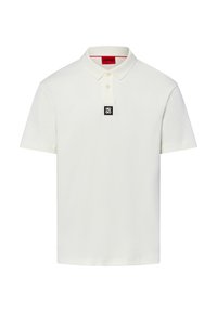 Polo blanca de algodón con cuello clásico, tapeta de dos botones y una etiqueta con logotipo negro en el frente. Mangas cortas, sin estampados.