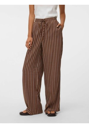 Pantalon marron ample à rayures blanches verticales, taille à cordon, poches latérales, porté avec des sandales noires et un haut blanc.