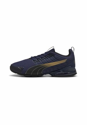 Heren navyblauwe atletieksneaker met zwart en goudkleurig Puma-logo, ademend mesh bovenwerk en een gevoerde zool op een witte achtergrond.