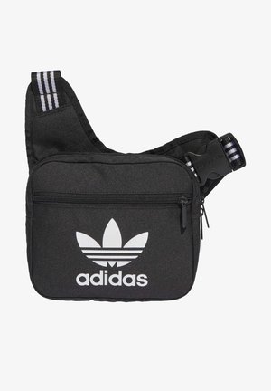 Schwarze Adidas Umhängetasche mit weißem Trefoil-Logo, vordere Reißverschlusstasche, verstellbarer Riemen mit schwarzen und weißen Streifen.