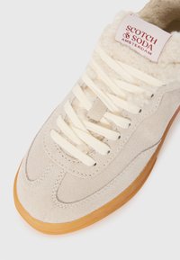 Sneaker in suede beige con lacci crema, fodera morbida e suola in gomma traslucida. Presenta un design cucito e un'etichetta con il marchio sul colletto.