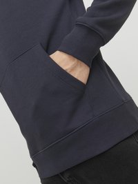 Marineblå sweatshirt med kengurulomme, ribbede manchetter og kant, der har en blød tekstur og en tætsiddende pasform.