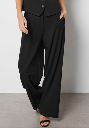 Czarne szerokie spodnie z gładkiego materiału, z wysokim stanem i przednimi plisami, wyposażone w boczne kieszenie i o luźnym kroju.