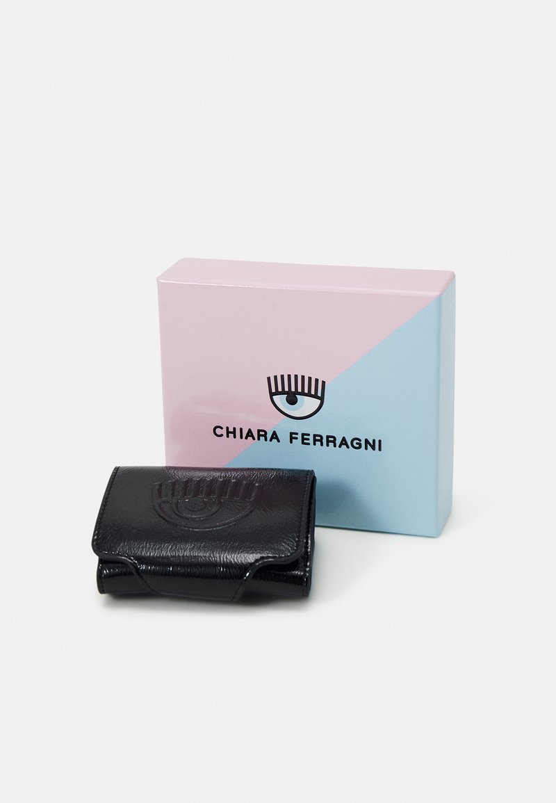 Schwarzes Lederportemonnaie mit geprägt Augen-Motiv, begleitet von einer zweifarbigen rosa-blauen Box mit dem Markennamen in schwarzem Text.