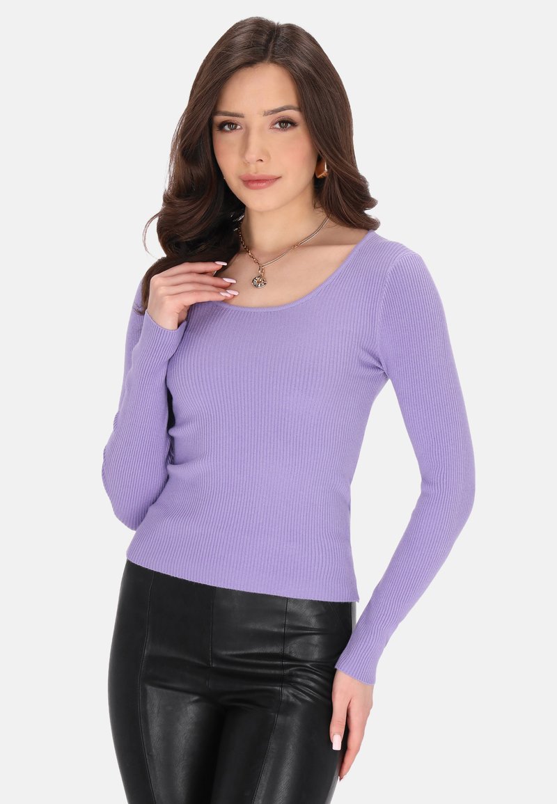 Lila geripptes Langarmoberteil mit Rundhalsausschnitt, taillierte Silhouette, getragen mit schwarzen Kunstlederhosen, minimalen Accessoires.