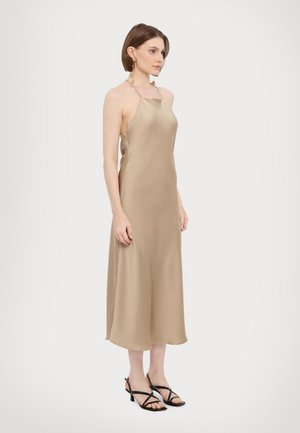 Beige satiini liukumekko ohuilla olkaimilla, virtaava siluetti ja nahkatason pituus. Mustat hihnakengät täydentävät asua.