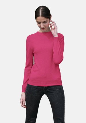 Pull en tricot rose ajusté avec un col rond côtelé et des manches longues ; détail texturé à l'avant et dos uni ; associé à un jean foncé.