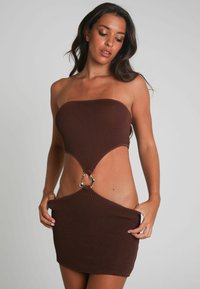 Robe bandeau marron en tissu texturé. Présente un design à découpe et des éléments en métal doré au centre, mettant en valeur une silhouette ajustée.