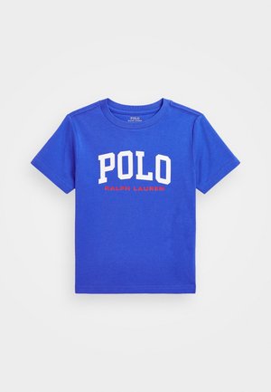Blå T-shirt med korte ærmer med hvid "POLO" og rød "RALPH LAUREN" tekst på fronten, rund hals, ensfarvet baggrund.