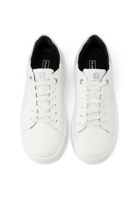 Un paio di sneakers bianche in pelle con lacci bianchi e rivestimento interno nero, viste dall'alto su uno sfondo bianco.