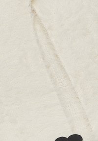 Cream-colored, fluffy knit fabric with a soft texture. Features a black heart-shaped accent near the bottom right corner.