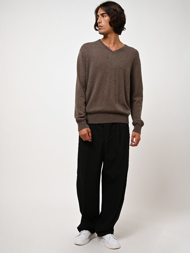 Maglione v-neck in lana marrone con maniche lunghe, abbinato a pantaloni neri a gamba larga e sneakers bianche. Tessuto morbido; vestibilità comoda.