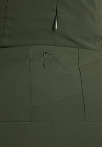 Tessuto verde oliva con una texture liscia; presenta una chiusura con cerniera e un dettaglio di tasca cucita con cuciture a contrasto.