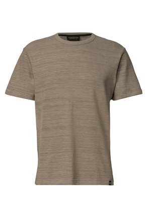 Mand iført en beige kortærmet t-shirt med rund hals, stående mod en ensfarvet lys baggrund, kigger let nedad.