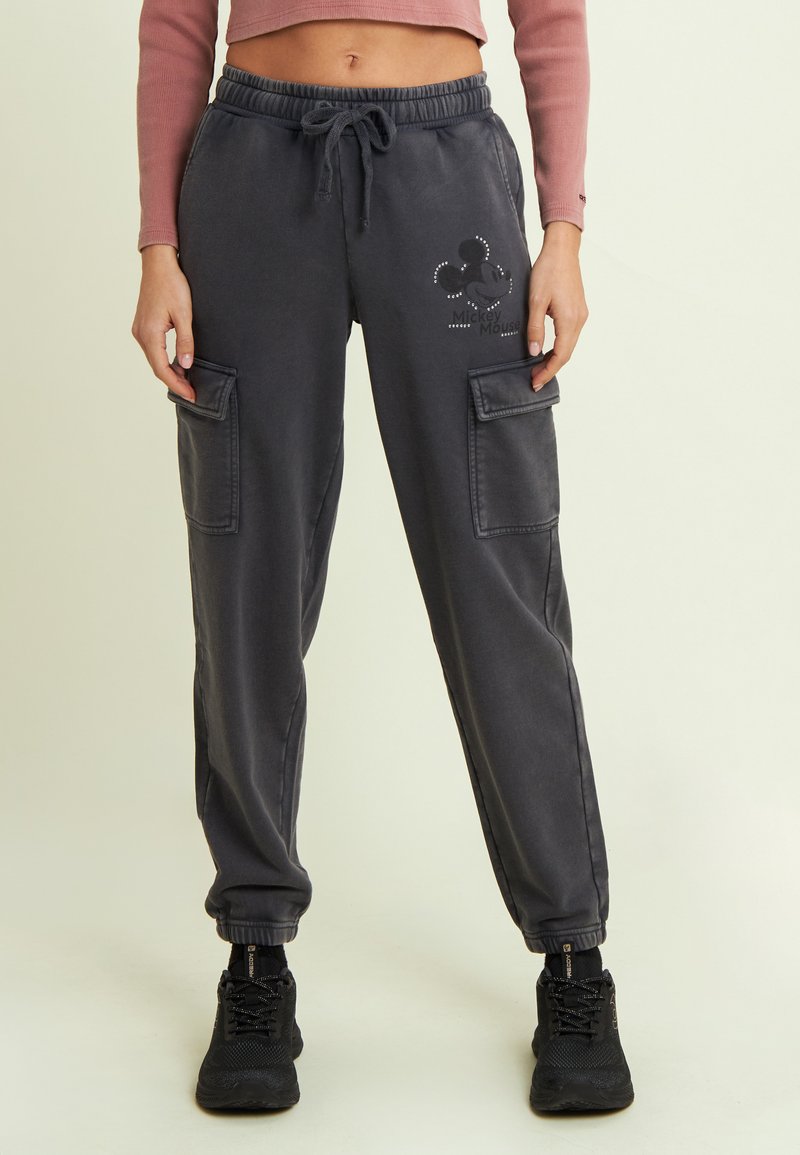 Pantalones de chándal grises con cintura elástica y cordón, dos bolsillos laterales tipo cargo, con un diseño impreso de Mickey Mouse y puños acanalados en los tobillos.