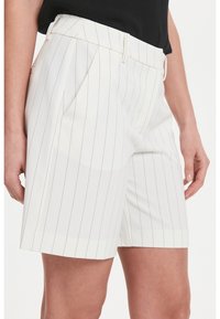 Bílé pruhované šortky s upraveným střihem, sklady vpředu a hladkým textilním povrchem. Disponují klasickým zakončením lemu.