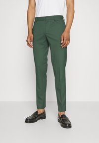 Zelene krojene hlače iz gladkega materiala, s flat sprednjim delom, z zankami za pas in slim fit, v kombinaciji s črnimi loafers.
