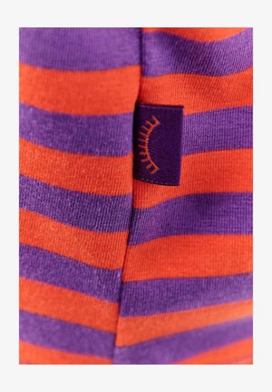 Skarpetki w paski z naprzemiennymi pomarańczowymi i fioletowymi kolorami, wykonane z miękkiej tkaniny, z małą fioletową metką z wzorem w krzywą linię.
