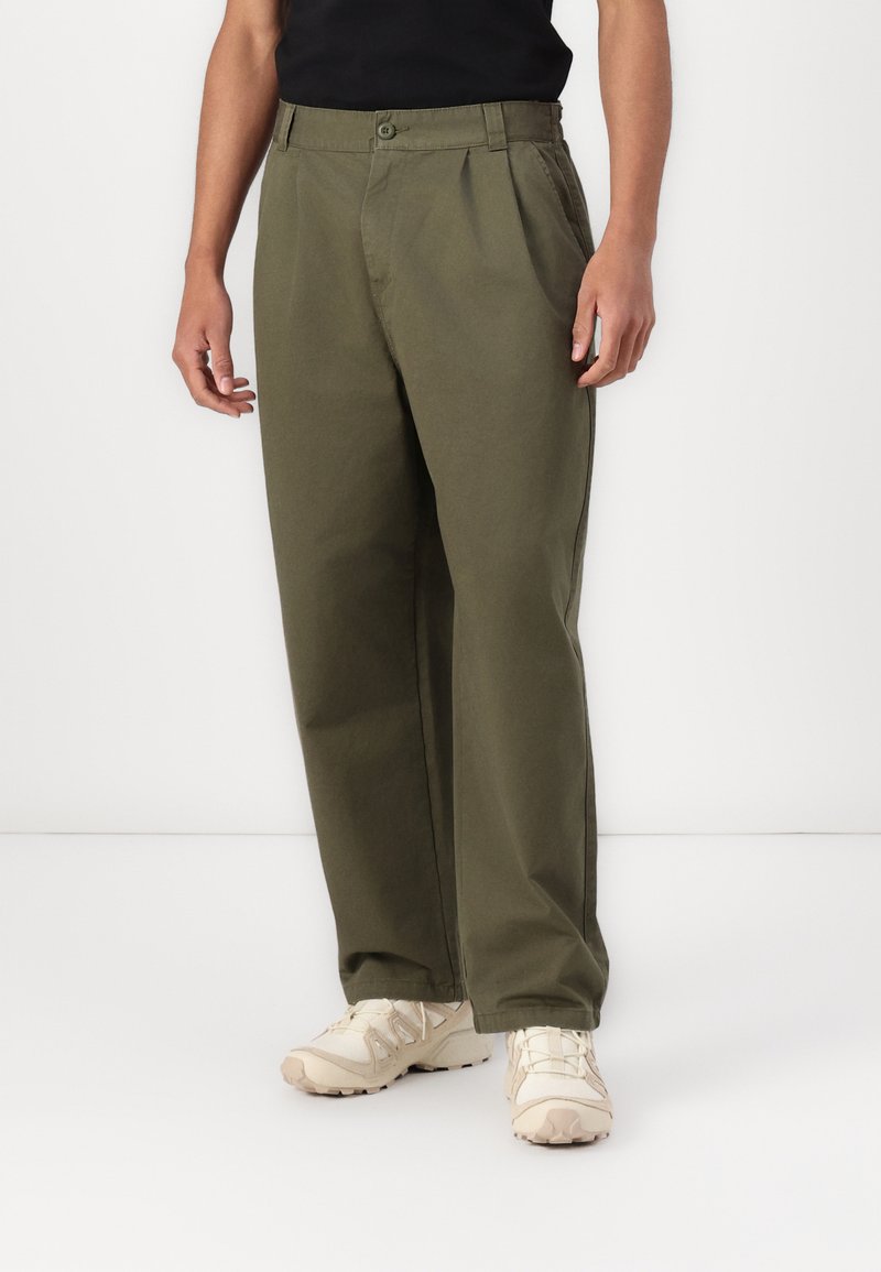 Olivengrønn, plisserte bukser laget av bomullsstoffblanding. Har en knappelukking, sidelommer og tapered ben-design.