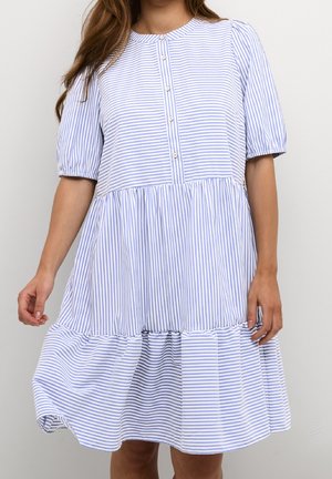 Woman wearing a blue and white vertical striped knee-length dress with short puff sleeves and a buttoned front placket.