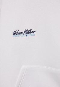 Witte sweatshirt met een geborduurd logo waarop 'Urban Mythos' staat in donker- en lichtblauw, voorzien van een voorkantzak en een zachte textuur.
