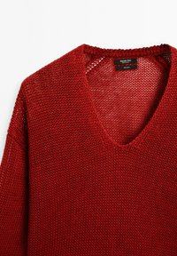 Maglione rosso lavorato a maglia con scollatura a V, caratterizzato da una trama ampia e aperta e dettagli a costine lungo il collo e i bordi.