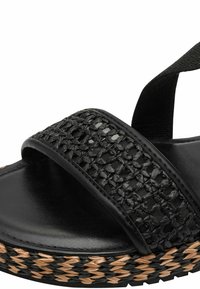 Sandales noires avec une bride tressée, une semelle intérieure en cuir lisse et une semelle en jute tressé avec des accents beige et noirs.