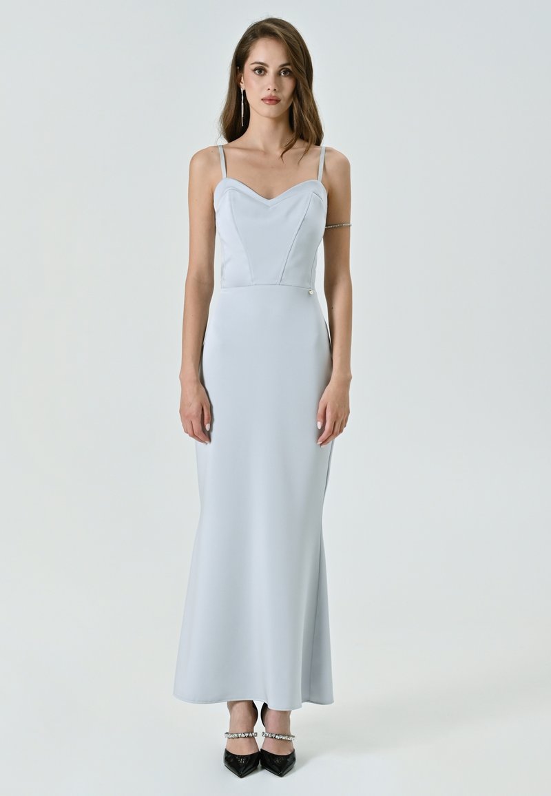 Abito da sera azzurro chiaro, aderente, con spalline sottili, scollatura a cuore e tessuto morbido. Presenta un dettaglio con bottoni laterali.