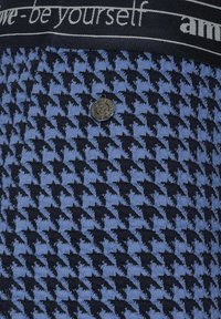 Látka s houndstooth vzorem v námořnické a světlomodré barvě s texturovaným povrchem, obsahující zaoblený černý logový knoflík a pružný pas s logem.