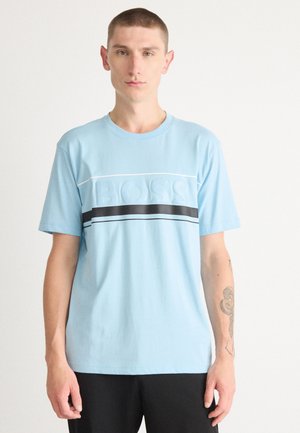 Camiseta de algodón azul claro con logo en relieve "BOSS" y franjas negras y blancas en el pecho, cuello redondo y mangas cortas.
