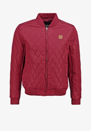 Sarkans kvilts apmales jaka ar ribotām piedurknēm un apakšmalu, sānu kabatām un logotipa uzšuvumu uz krūtīm. Gluda auduma, vidēja garuma dizains.