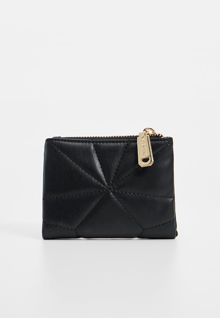 Portafoglio a monete in pelle nera trapuntata con cuciture geometriche e una linguetta dorata per la zip su uno sfondo semplice.