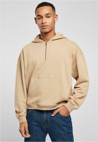 Felpa con zip beige, dotata di una tasca frontale, caratterizzata da una vestibilità comoda e polsini a coste. Realizzata in morbido tessuto misto cotone.