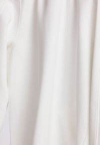 Witte langmouwtop gemaakt van zachte stof met een gladde textuur. Heeft een eenvoudig ontwerp en een lichte draping. Geen zichtbare patronen of hardware.