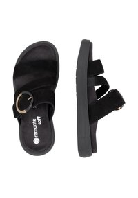 Black slide sandals made of soft suede, featuring two wide straps and a circular metal accent for adjustment. Textured sole, casual design.