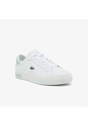 Niski biały sneaker z zielonymi akcentami, wiązany na sznurówki oraz z małym zielonym logo krokodyla po boku.