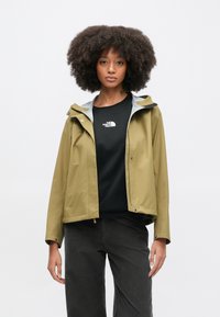 Αδιάβροχο μπουφάν σε ελιά πράσινο με γκρι εσωτερική επένδυση, ρυθμιζόμενη κουκούλα, μπροστινό κλείσιμο με κουμπιά και μαύρο λογότυπο πάνω σε μαύρο πουκάμισο από κάτω.