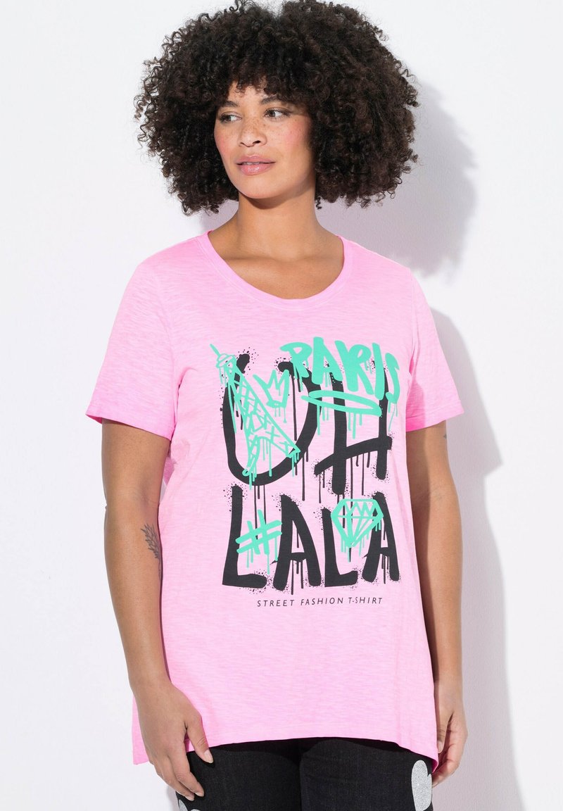 Roze T-shirt met korte mouwen van lichte stof, voorzien van zwarte en groene graffiti-stijl tekst "Paris Oh La La" met een diamantafbeelding.