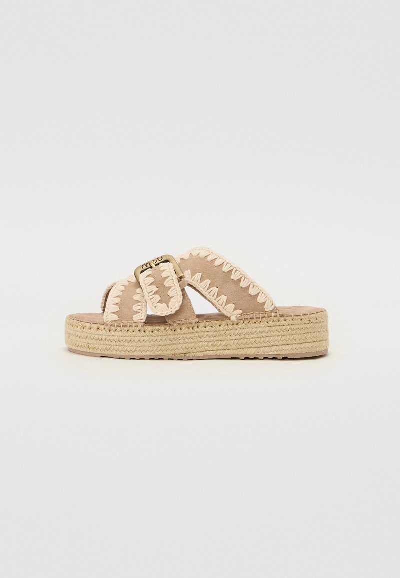 Sandales de plateforme en daim beige clair avec un design à deux sangles, accentuées par une couture zigzag rose et une boucle en métal sur l'une des sangles.