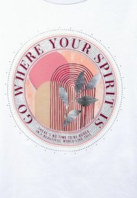 Biała koszulka z okrągłą grafiką przedstawiającą kolorowe kształty, akcenty z srebrnego liścia oraz napisem "Idź tam, gdzie jest Twój duch."